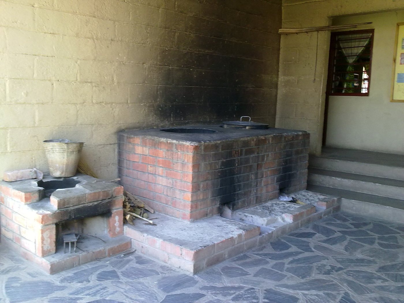A brick institutional rocket stove built up as a masonry block with sunken pot seats