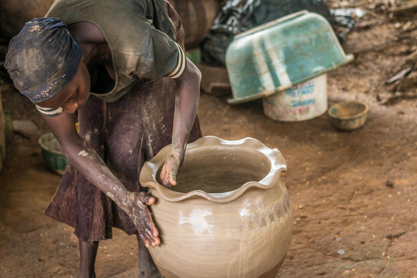 Women hand-building large clay water jars at a pottery village