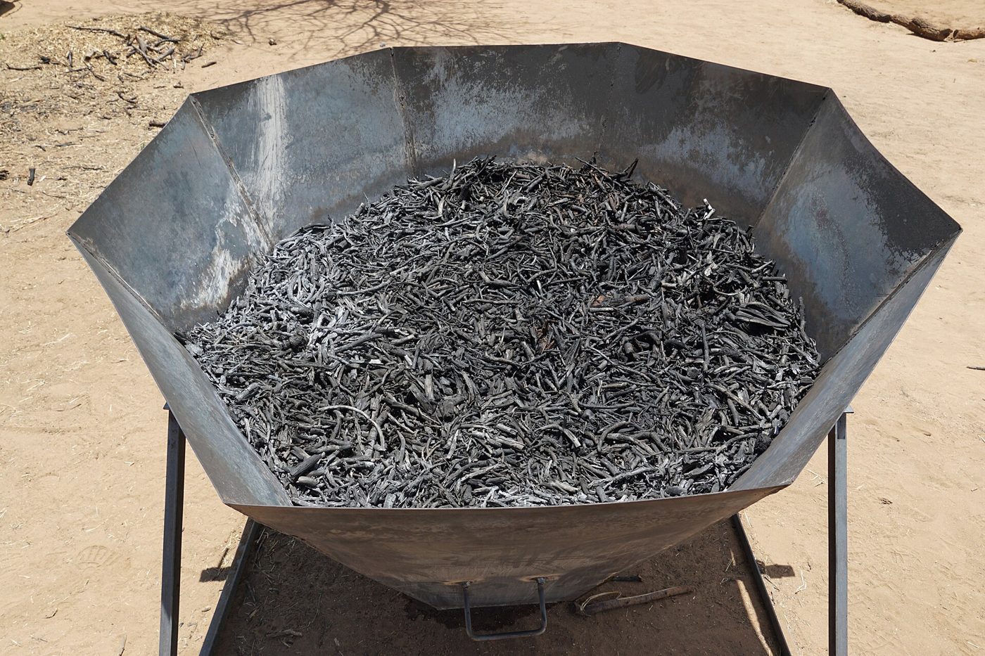 A steel Kon-Tiki cone kiln in Namibia holding a finished batch of biochar