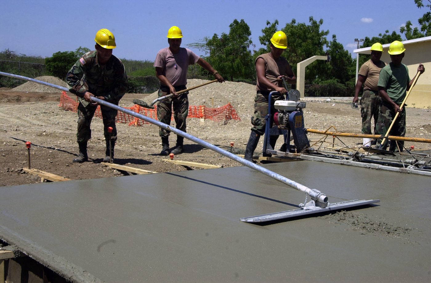 Workers screeding and floating a freshly poured floor slab level