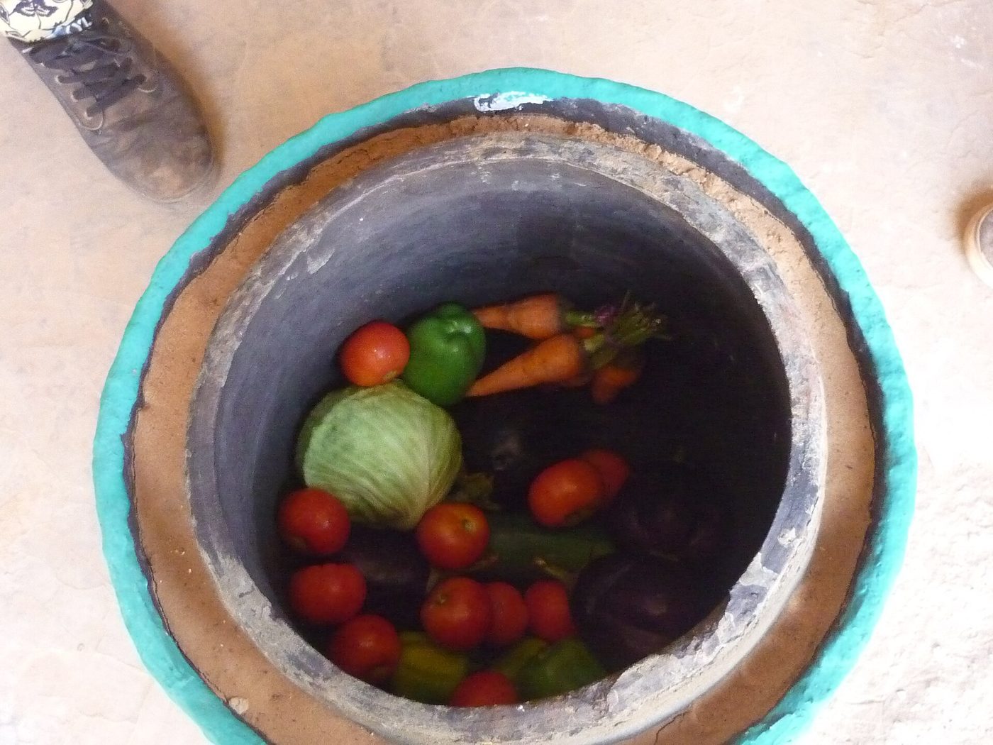 A clay pot-in-pot evaporative cooler filled with vegetables
