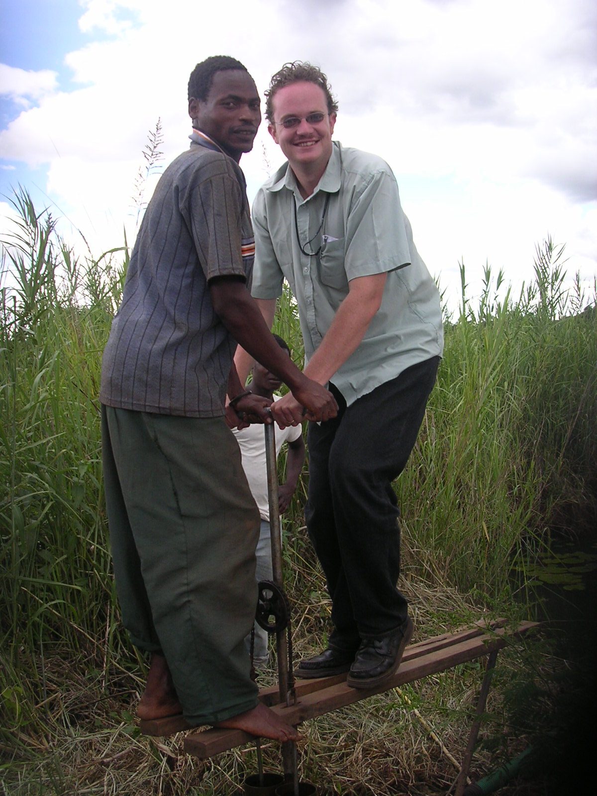 A treadle pump being demonstrated in Malawi, operator stepping on the twin pedals
