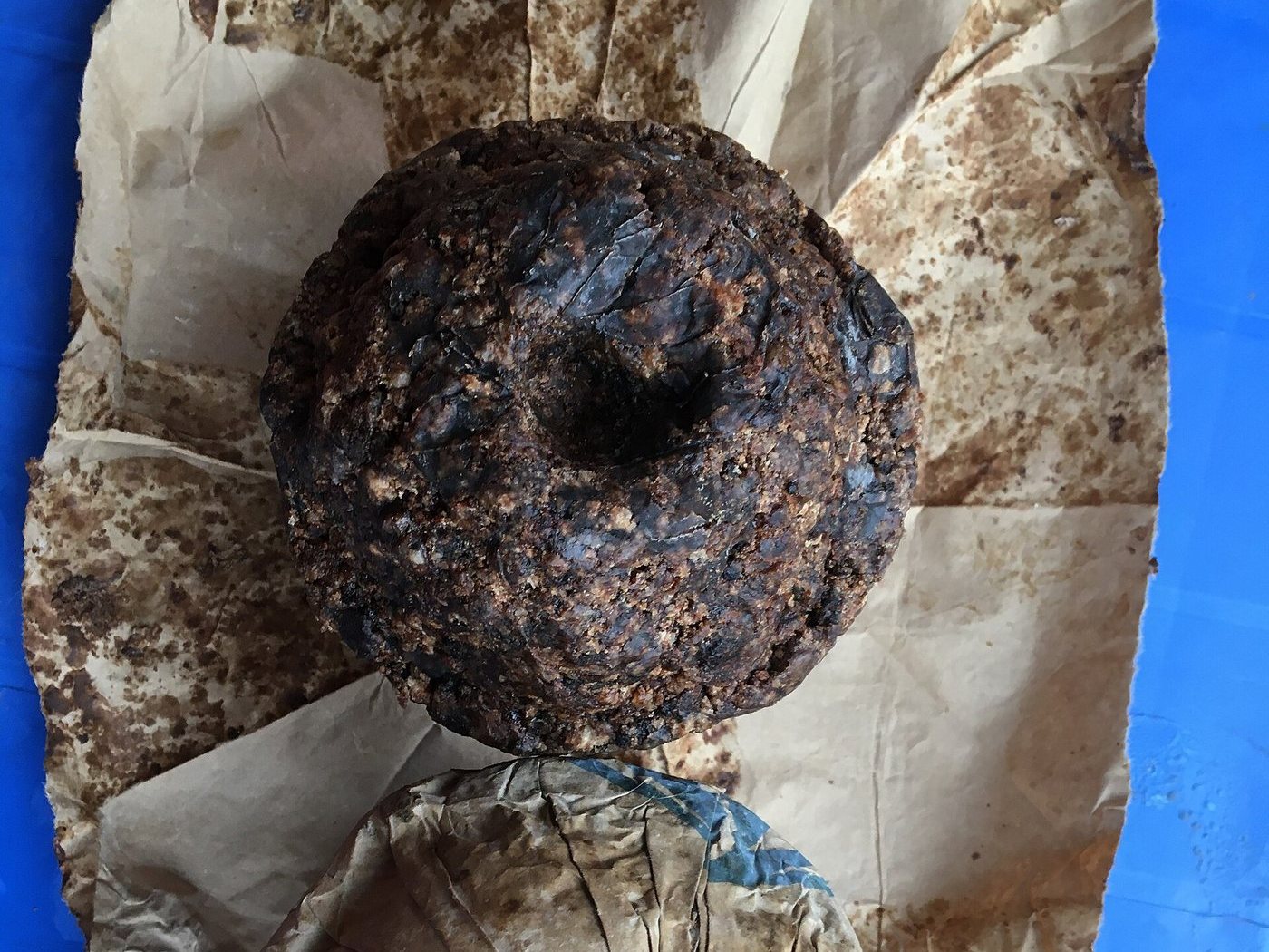 A finished cake of Alata Samina black soap resting on paper after curing