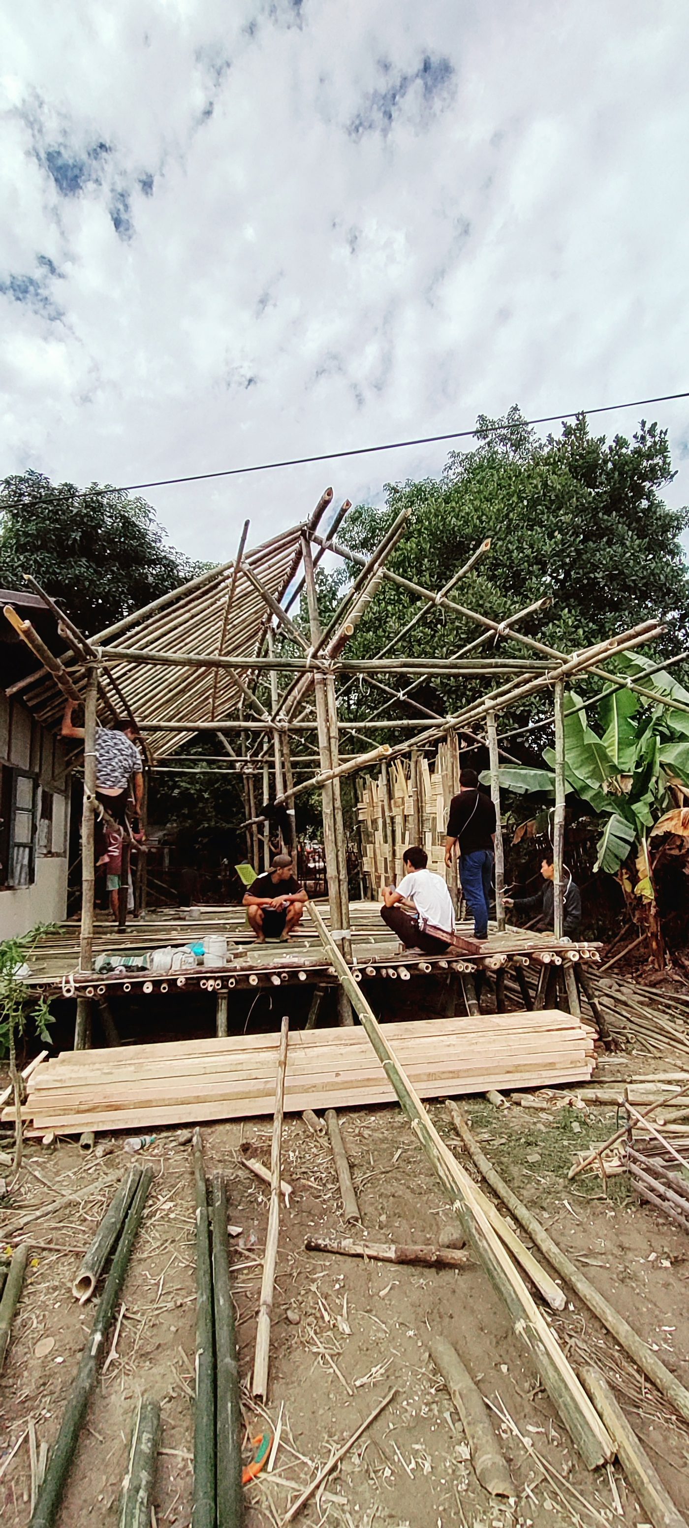Bamboo poles lashed and pinned into a house frame and roof structure under construction