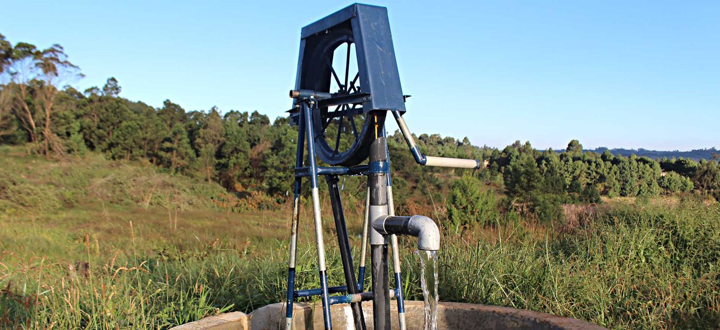 A rope pump installed over a well, lifting water with a looped rope and washers