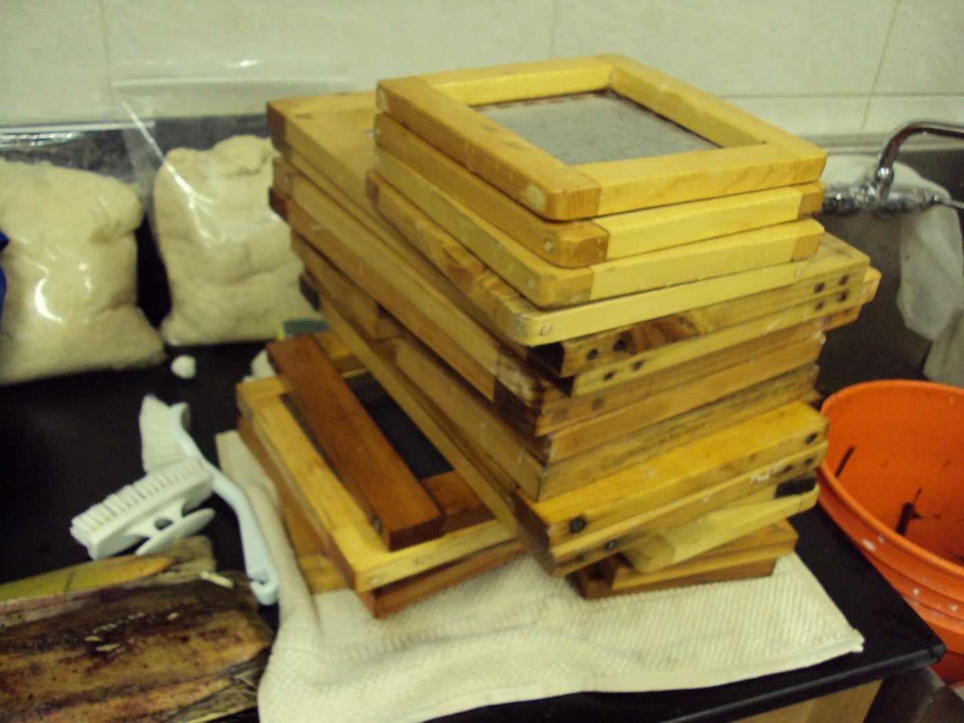 Papermaking moulds and deckles stacked beside pulp ready for sheet forming