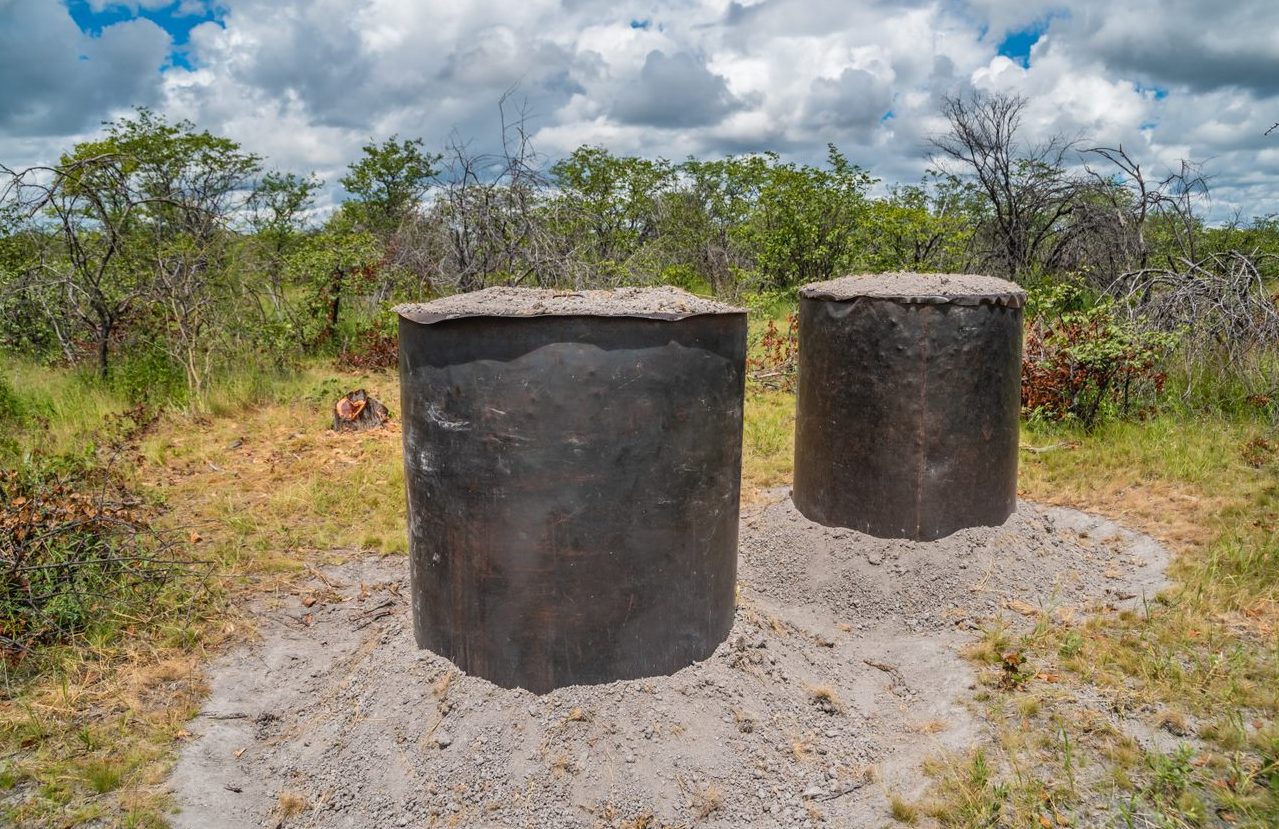 Steel drum charcoal kilns set into the ground for a controlled burn