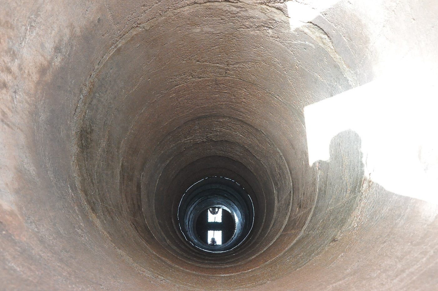 Looking down a hand-dug well lined with stacked concrete rings